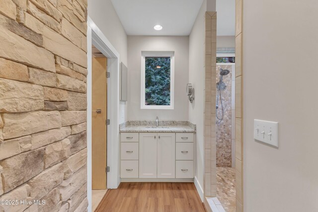 full bathroom with walk in shower, vanity, and wood finished floors