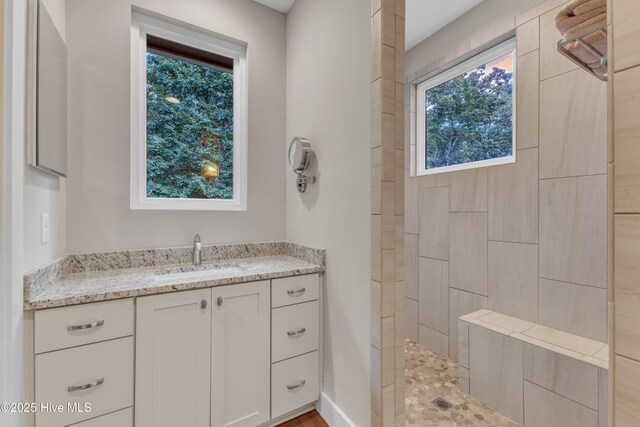 full bath featuring a walk in shower and vanity