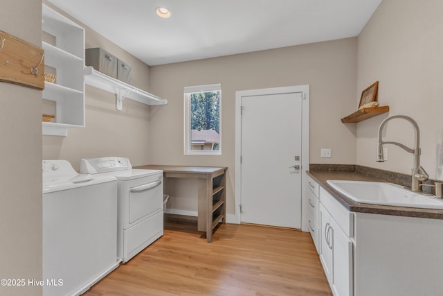 washroom featuring light wood-style flooring, cabinet space, a sink, and washer and clothes dryer