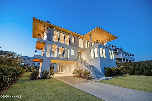 rear view of house with a balcony, stairs, and a lawn