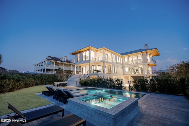 back of house with a fenced in pool, a patio, stairway, a balcony, and an in ground hot tub