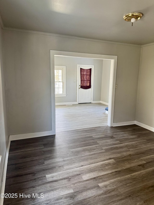 empty room with baseboards, ornamental molding, and wood finished floors