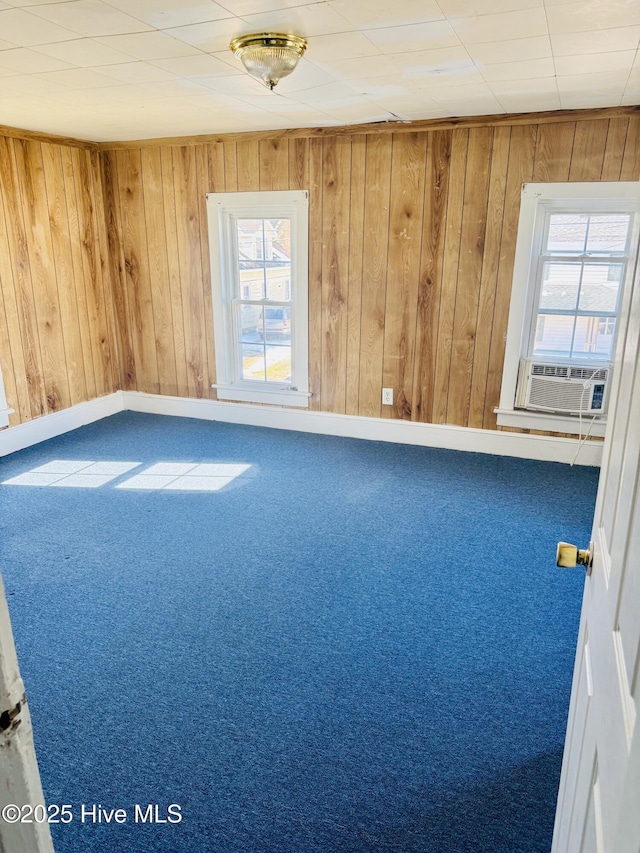 carpeted empty room with wood walls, baseboards, and cooling unit