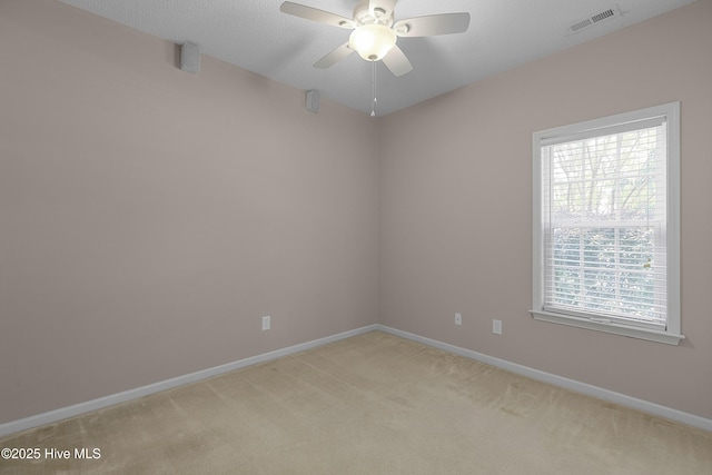 empty room featuring a ceiling fan, baseboards, visible vents, and light colored carpet