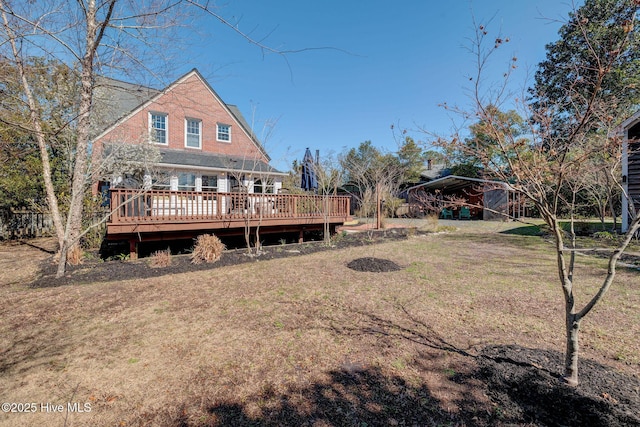 rear view of house featuring a deck, a carport, and a yard