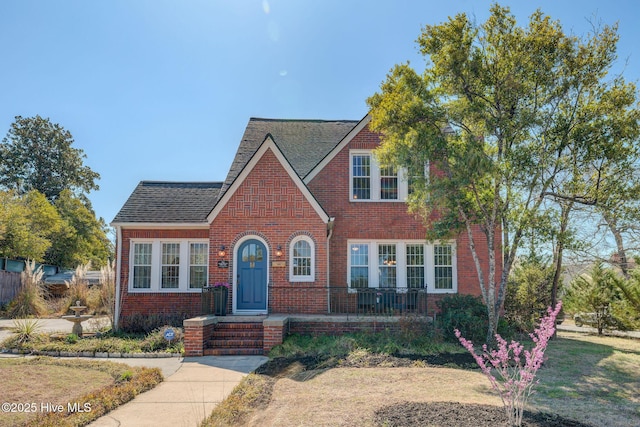 english style home with brick siding and roof with shingles