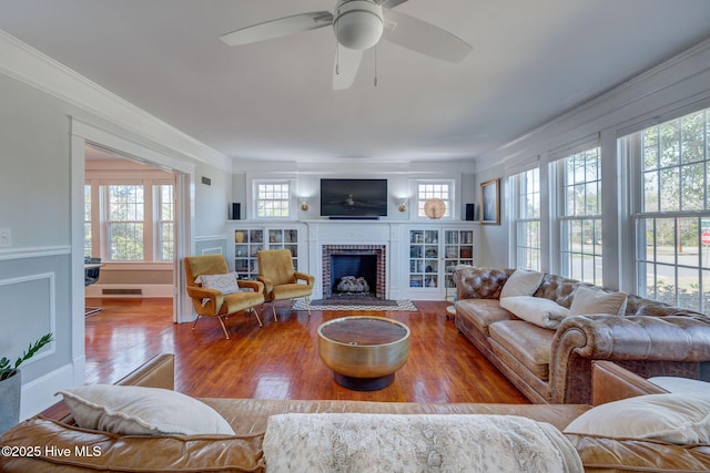 living room featuring visible vents, a fireplace, crown molding, and wood finished floors