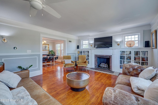 living area featuring plenty of natural light, ornamental molding, a brick fireplace, and wood finished floors