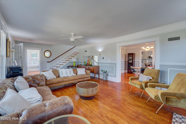 living room with visible vents, stairs, ornamental molding, wood finished floors, and a decorative wall