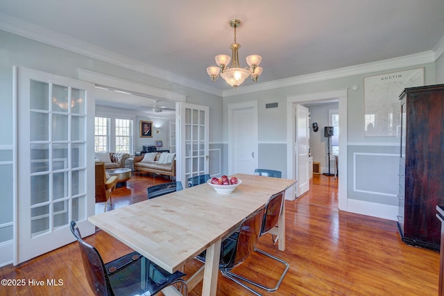 dining area featuring ceiling fan with notable chandelier, crown molding, wood finished floors, and visible vents