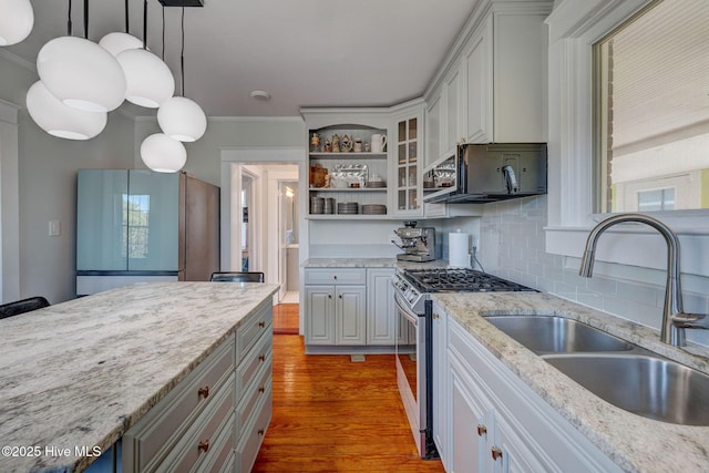 kitchen featuring open shelves, black microwave, refrigerator with glass door, stainless steel gas range, and a sink