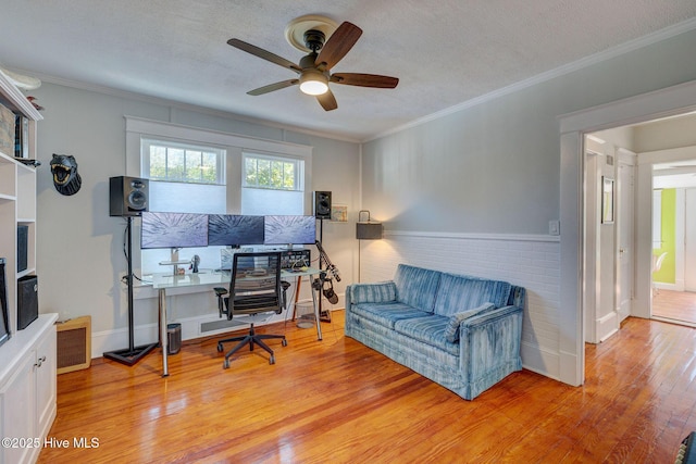 office space with a textured ceiling, light wood-style flooring, ceiling fan, and ornamental molding