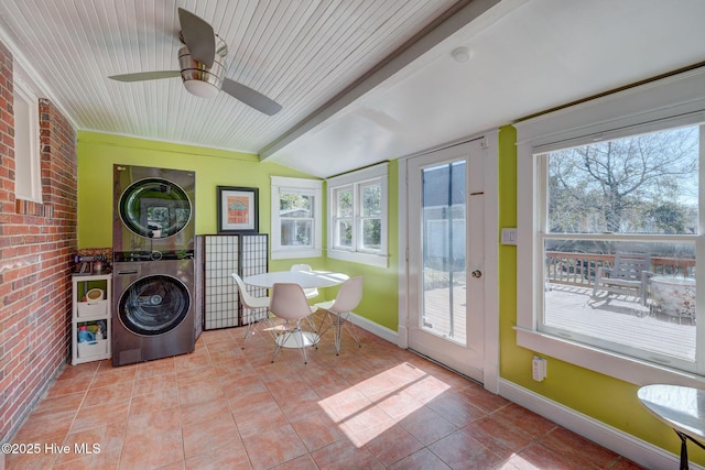 sunroom featuring ceiling fan, plenty of natural light, vaulted ceiling with beams, and stacked washing maching and dryer