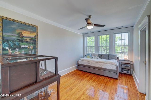 bedroom featuring visible vents, baseboards, light wood-type flooring, ornamental molding, and a ceiling fan