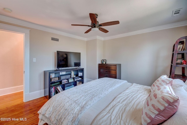 bedroom featuring visible vents, ornamental molding, baseboards, and wood finished floors