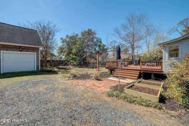 view of yard with fence, a deck, and a garden