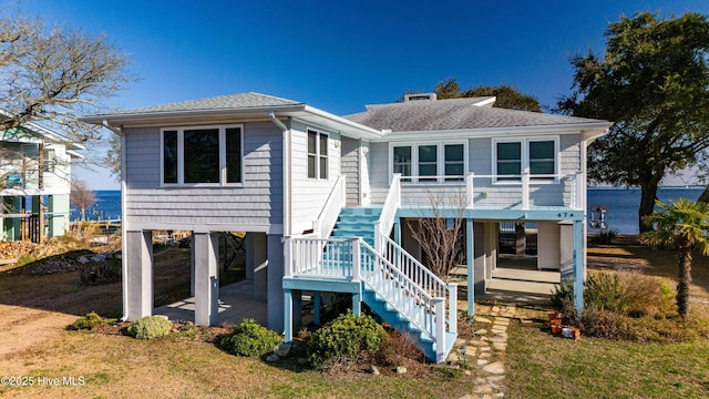 view of front of home with a carport, a patio area, roof with shingles, and stairway