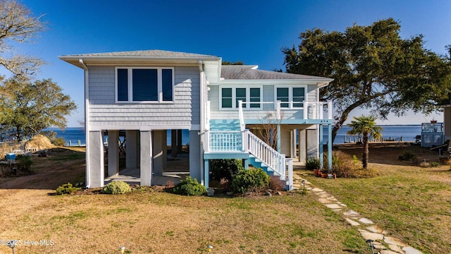 back of property with a shingled roof, a lawn, a patio, and stairs