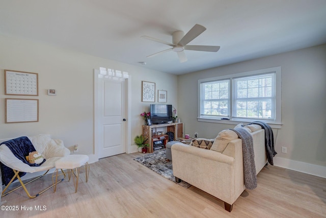 living room featuring a ceiling fan, baseboards, and wood finished floors