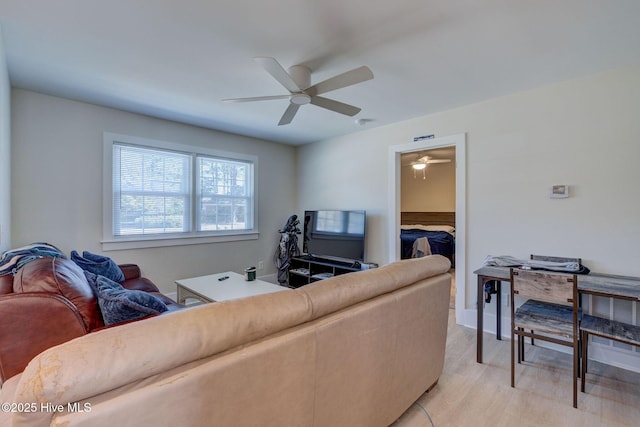 living area featuring light wood-style flooring and a ceiling fan