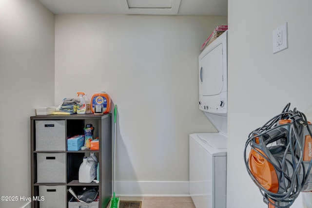 laundry room featuring laundry area, stacked washer / dryer, attic access, and baseboards