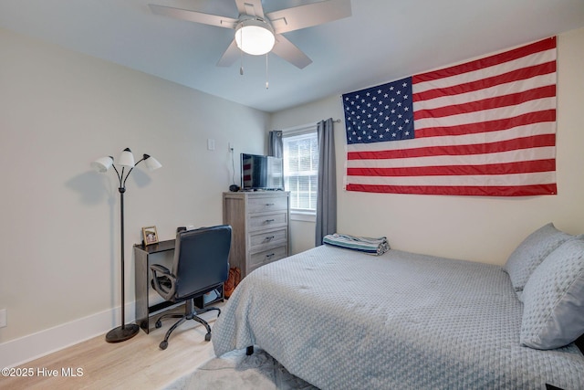 bedroom with a ceiling fan, baseboards, and wood finished floors