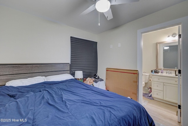 bedroom with light wood-style floors, ensuite bath, and a ceiling fan