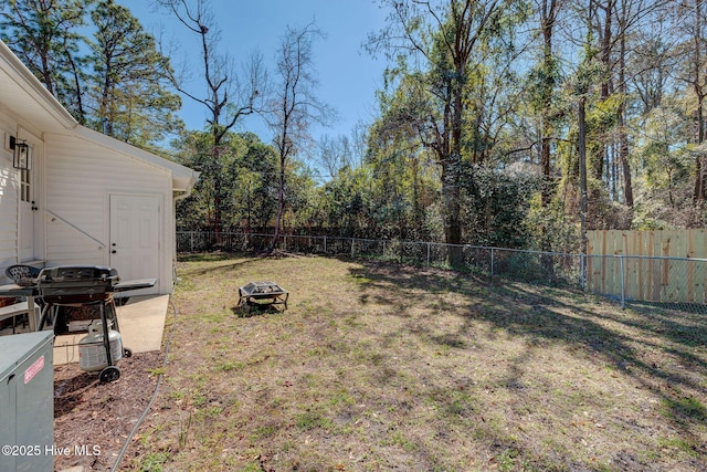 view of yard featuring a fenced backyard and a fire pit