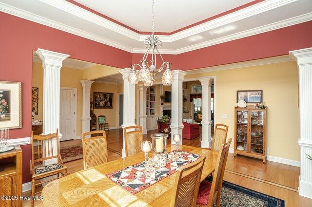 dining room featuring ornate columns, baseboards, and wood finished floors