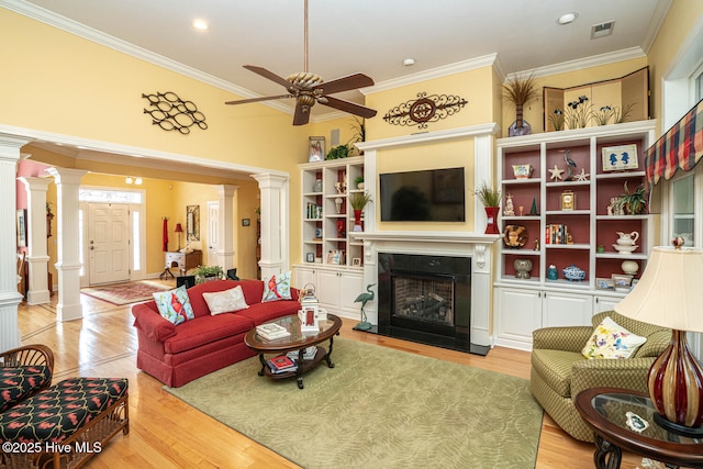 living area with light wood-type flooring, ornate columns, a fireplace, and visible vents