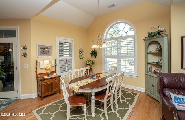 dining area with lofted ceiling, light wood finished floors, plenty of natural light, and visible vents