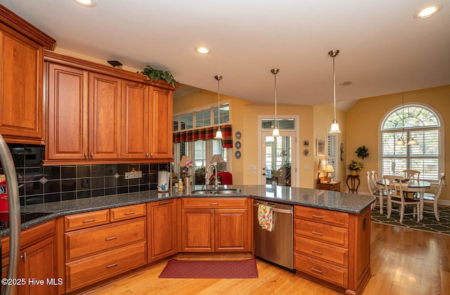 kitchen featuring a sink, a peninsula, brown cabinetry, and stainless steel dishwasher