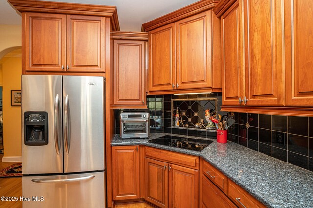 kitchen featuring arched walkways, stainless steel refrigerator with ice dispenser, and brown cabinets