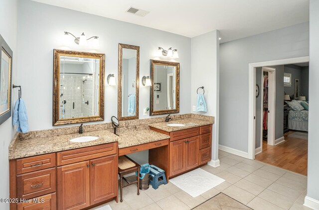 full bath with double vanity, tiled shower, a sink, and visible vents