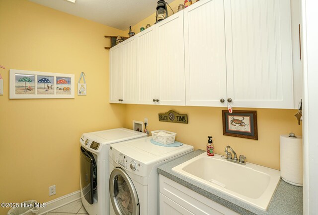 laundry area with washing machine and clothes dryer, cabinet space, a sink, baseboards, and tile patterned floors