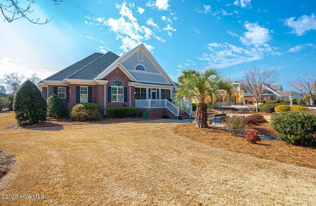 view of front of property featuring brick siding, roof with shingles, and a front yard