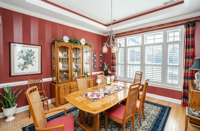 dining area featuring baseboards, visible vents, ornamental molding, and wood finished floors