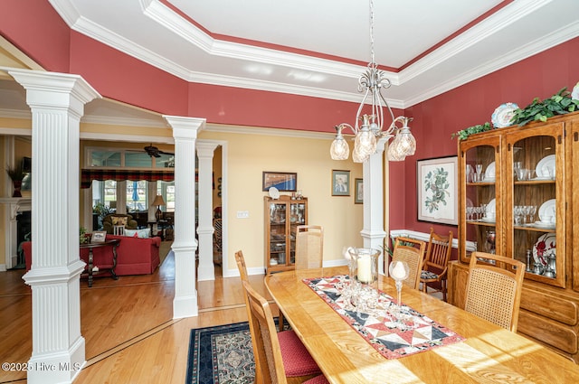 dining area featuring wood finished floors, a ceiling fan, and ornate columns