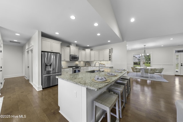 kitchen with decorative backsplash, dark wood finished floors, light stone counters, stainless steel appliances, and a sink