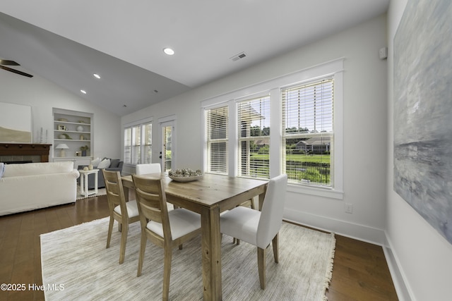 dining area featuring built in shelves, a healthy amount of sunlight, vaulted ceiling, and baseboards