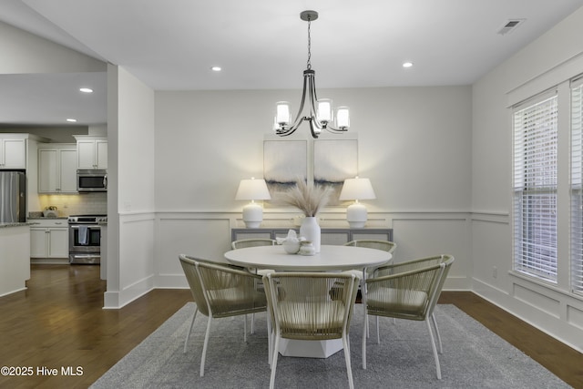 dining room with dark wood-style floors, a wainscoted wall, visible vents, and a notable chandelier