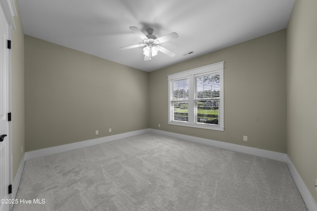 carpeted empty room featuring baseboards, visible vents, and a ceiling fan