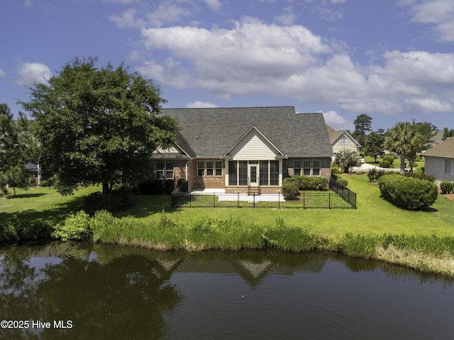 back of property with a yard, brick siding, a water view, and a fenced backyard