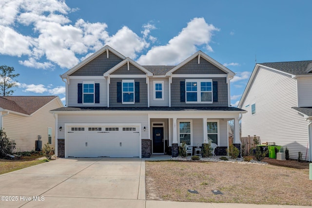 craftsman inspired home featuring concrete driveway, a porch, central AC unit, and a garage