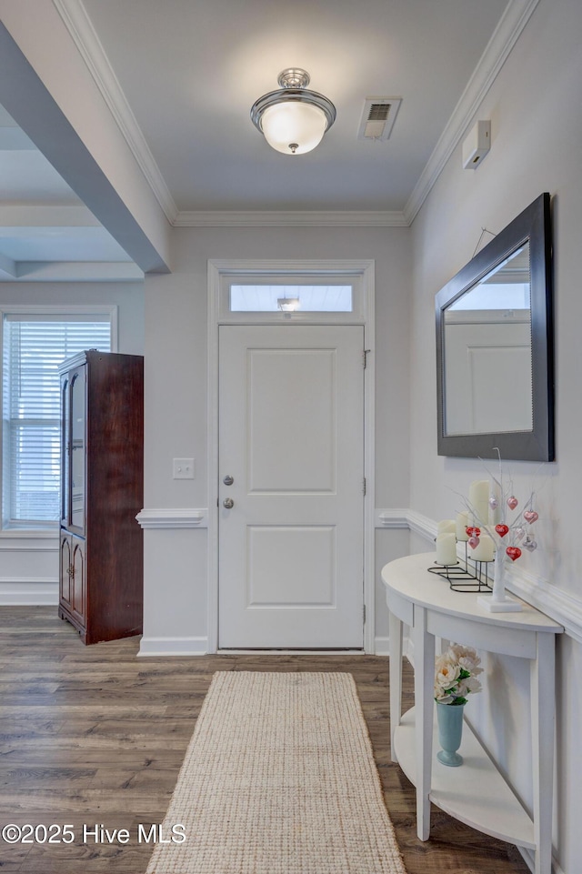 foyer with crown molding, wood finished floors, visible vents, and baseboards