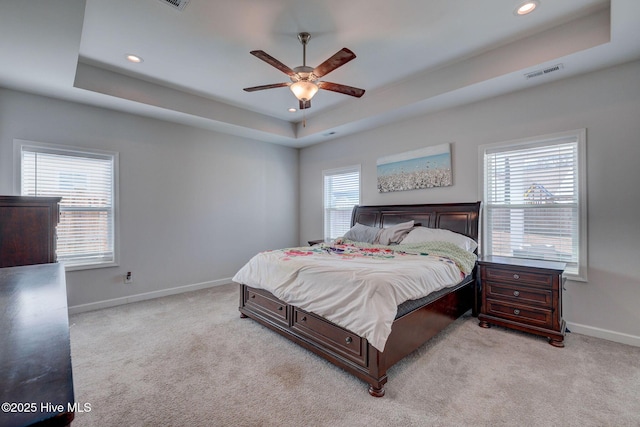 carpeted bedroom with a tray ceiling, baseboards, and visible vents