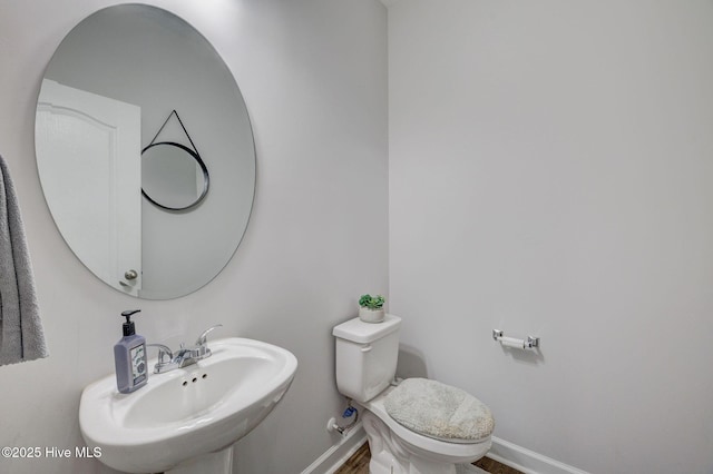 half bath with a sink, baseboards, and toilet