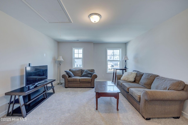 living area featuring attic access, baseboards, and light carpet