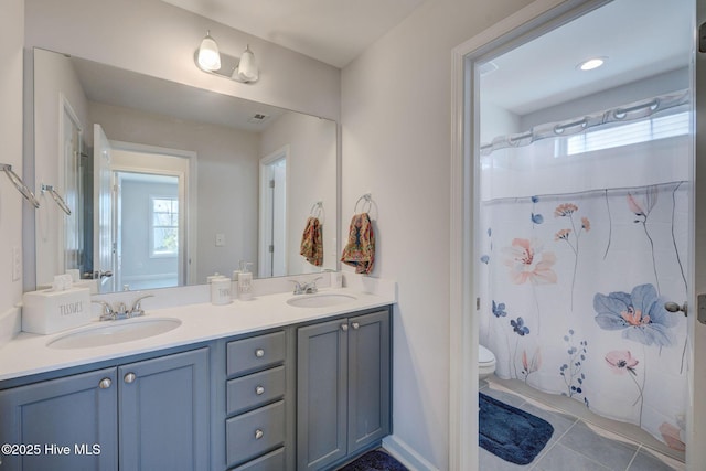 bathroom with tile patterned flooring, double vanity, toilet, and a sink