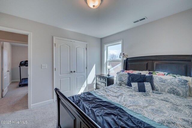 bedroom with baseboards, visible vents, a closet, and light carpet